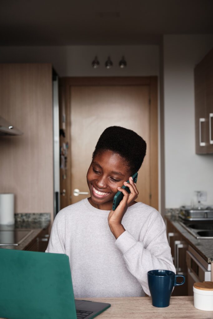 Content black female freelancer having phone conversation while working on computer